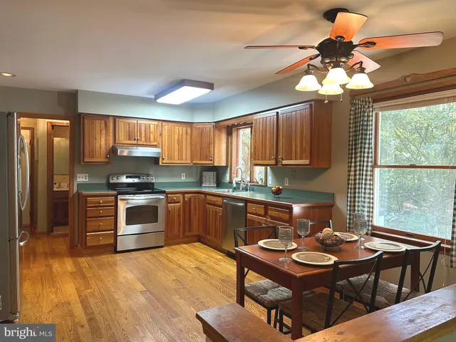 a kitchen with a stove a sink dishwasher a dining table and chairs with wooden floor