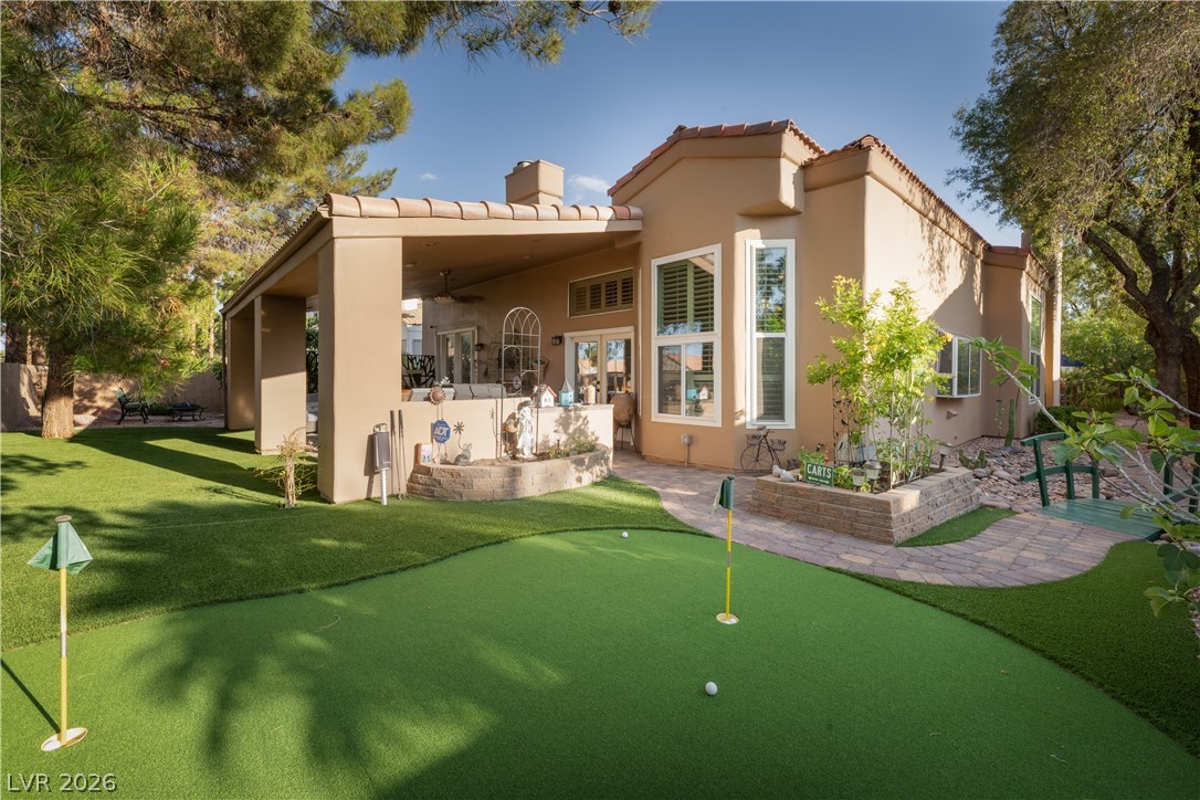 2108 Inverness Drive Henderson, NV 89074 - Photo 12 of 46 Back of house with an area to practice putting, stucco siding, a ceiling fan, a tile roof, and a patio