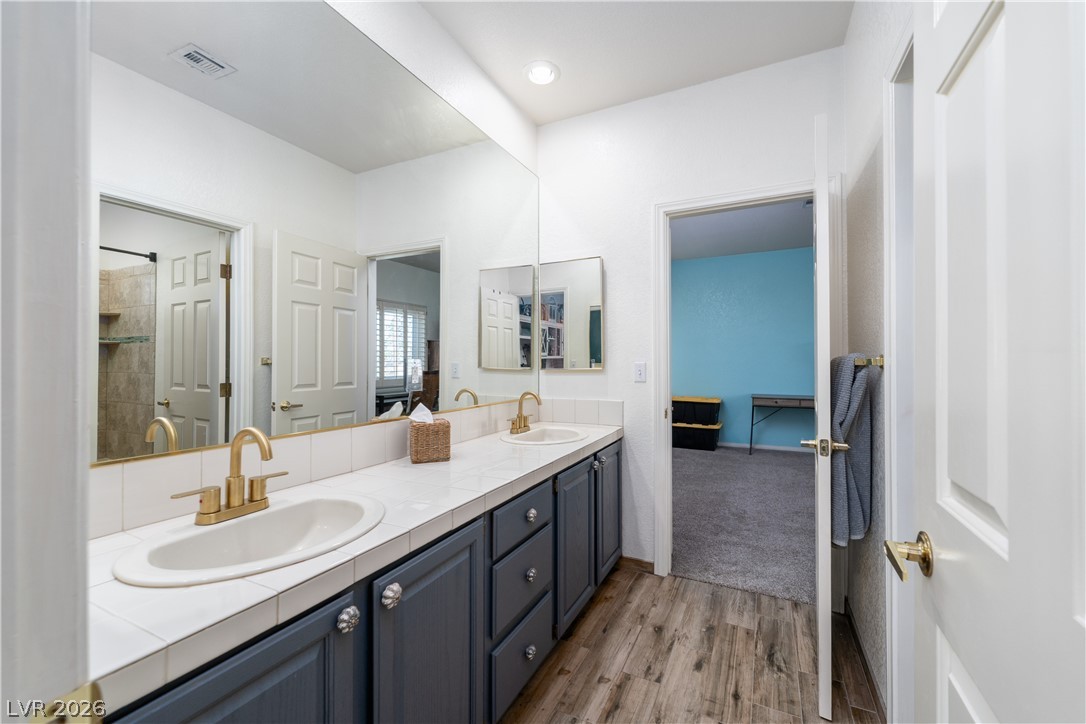 2108 Inverness Drive Henderson, NV 89074 - Photo 29 of 46 Bathroom featuring double vanity, wood finished floors, and tiled shower