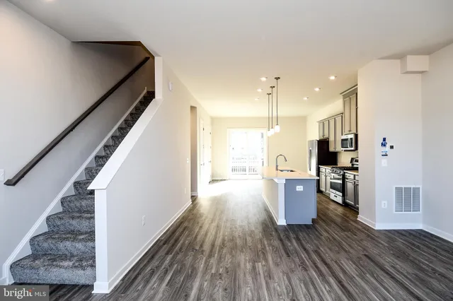 a kitchen with stainless steel appliances granite countertop a refrigerator a sink dishwasher a stove and white countertops with wooden floor