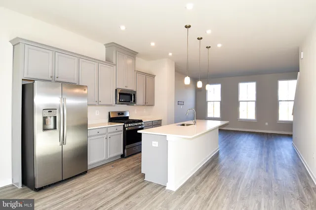 a large kitchen with stainless steel appliances kitchen island a large counter top and wooden floors