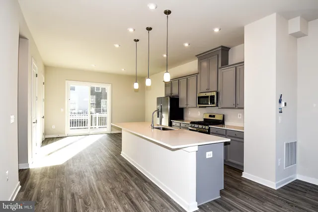 a kitchen with a stove a sink a refrigerator and a wooden floor