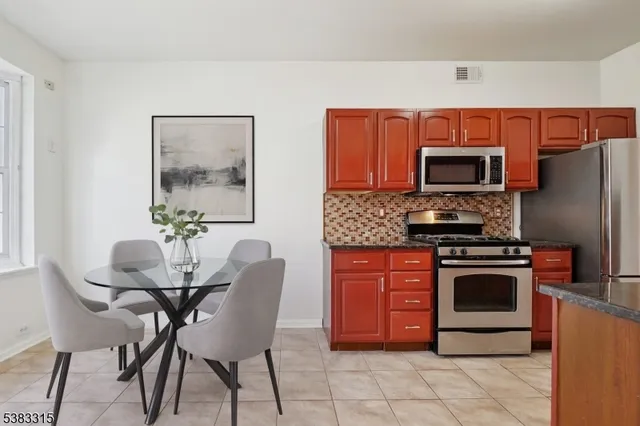 a kitchen with stainless steel appliances a stove a sink refrigerator and a chair