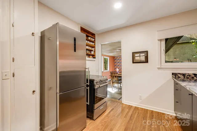 a kitchen with stainless steel appliances granite countertop a refrigerator a stove and a wooden floor