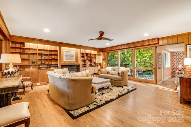 a living room with furniture large windows plants and wooden floor