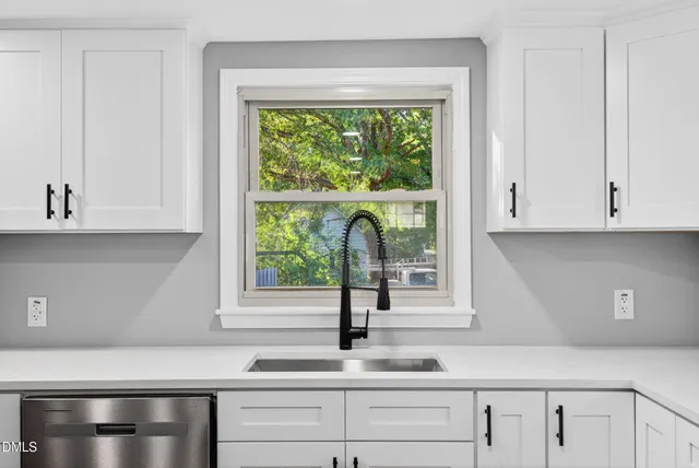 a kitchen with white cabinets and a window