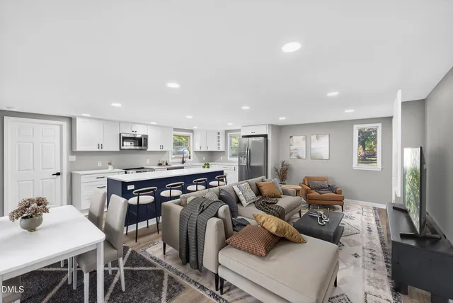 a living room with furniture a flat screen tv and kitchen view