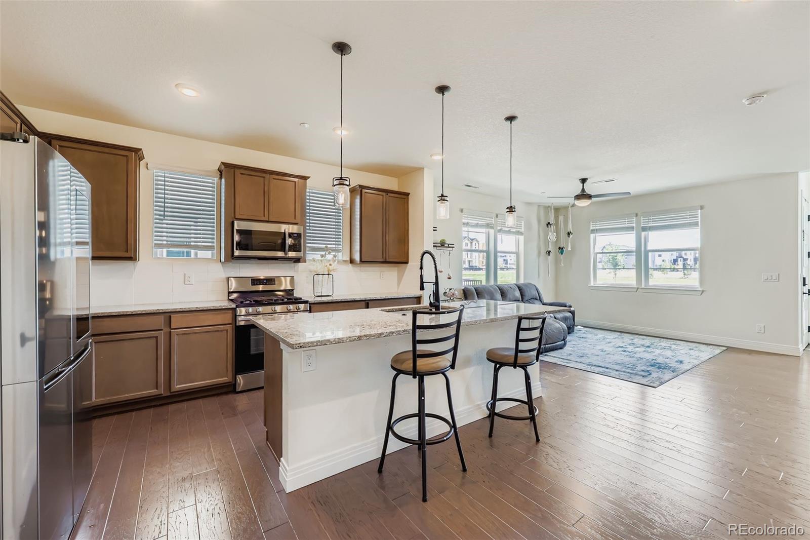 1835 Rose Quartz Heights Colorado Springs, CO 80908 - Photo 11 of 31 a kitchen with stainless steel appliances granite countertop a stove top oven a sink a dining table and chairs with wooden floor