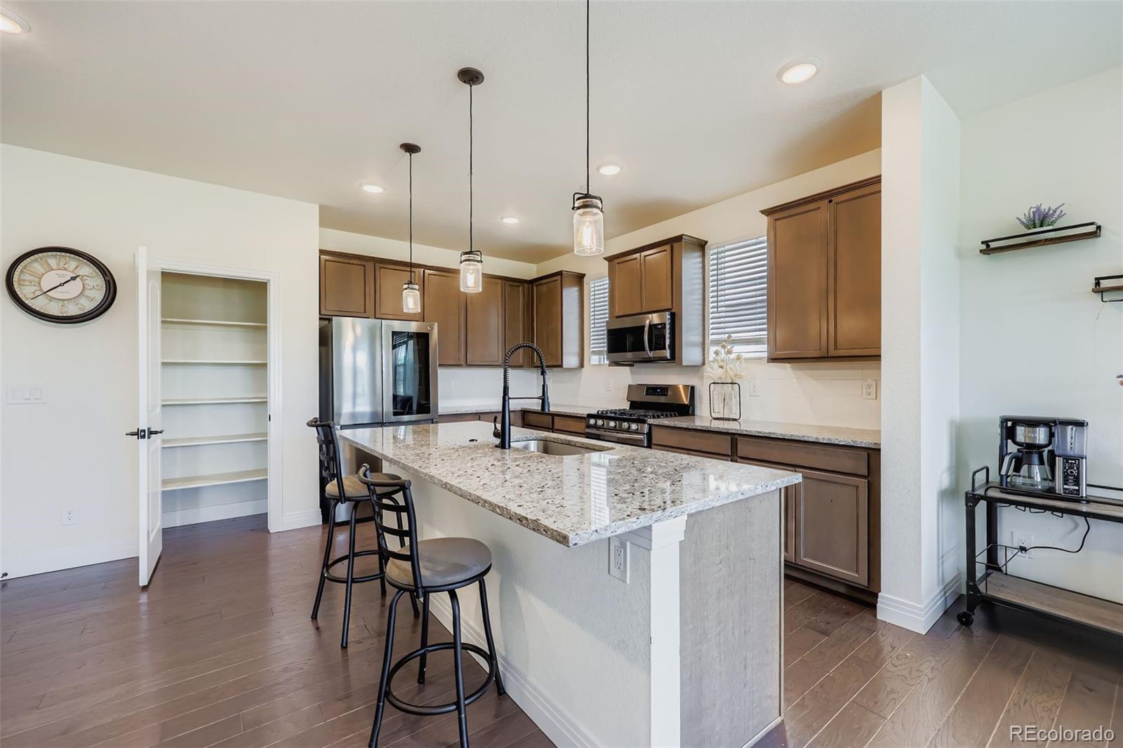1835 Rose Quartz Heights Colorado Springs, CO 80908 - Photo 12 of 31 a kitchen with granite countertop a stove a sink a oven a refrigerator and a table with wooden floor