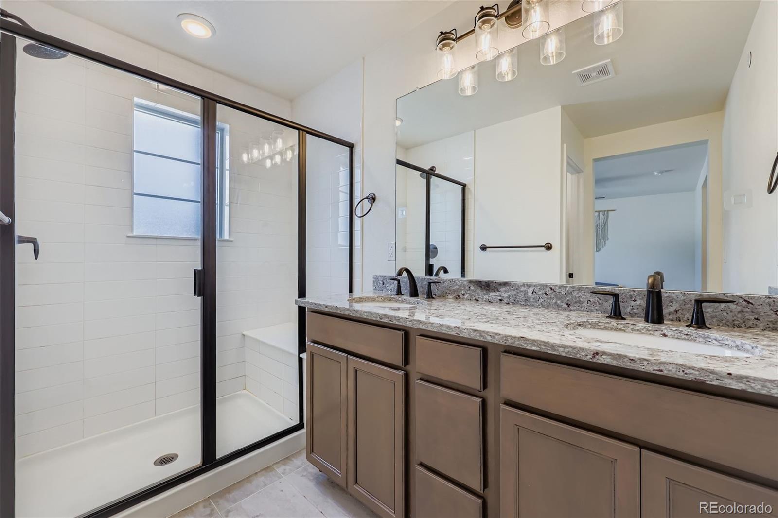 1835 Rose Quartz Heights Colorado Springs, CO 80908 - Photo 17 of 31 a bathroom with a granite countertop double vanity sink and mirror