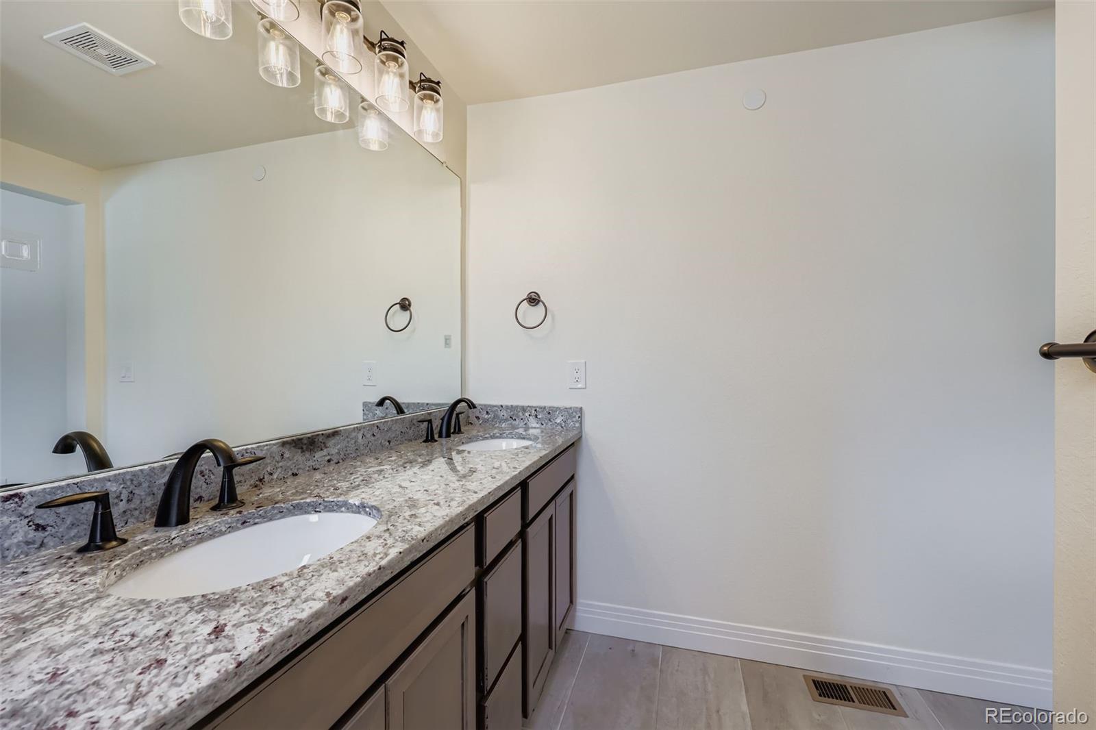 1835 Rose Quartz Heights Colorado Springs, CO 80908 - Photo 18 of 31 a bathroom with a granite countertop sink and a mirror