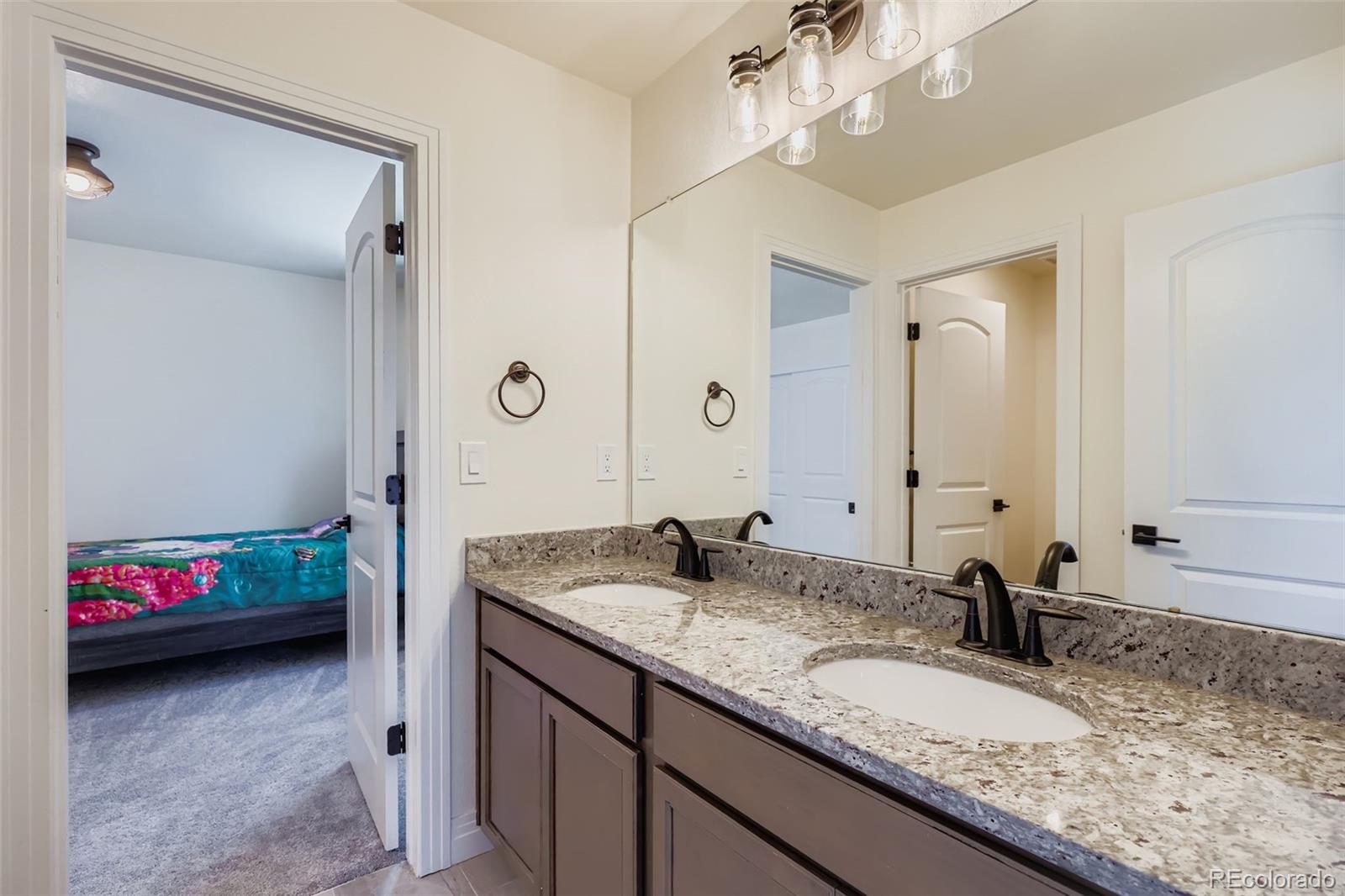1835 Rose Quartz Heights Colorado Springs, CO 80908 - Photo 25 of 31 a en suite bathroom with a granite countertop double vanity sink and a mirror