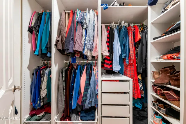 a view of walk in closet with clothes and shoes