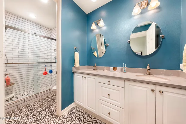 a bathroom with a double vanity sink mirror and shower