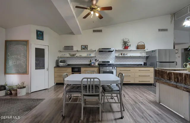 a kitchen with stainless steel appliances a dining table chairs and wooden floor