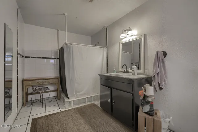 a bathroom with a sink a mirror a lamp and a shower