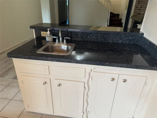 a kitchen with granite countertop white cabinets and sink