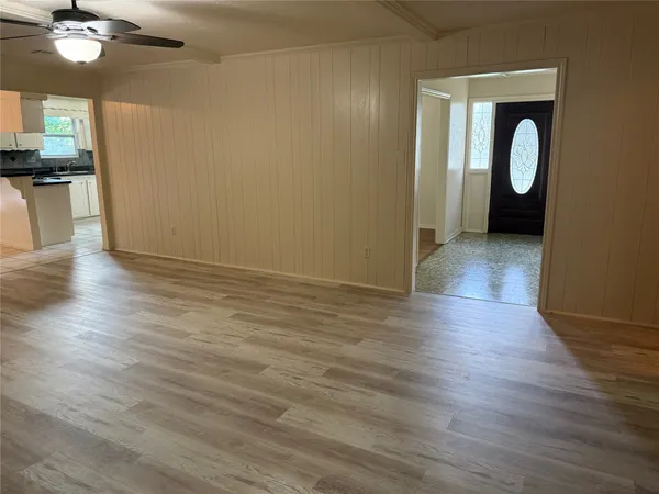 a view of an empty room with wooden floor and a bathroom