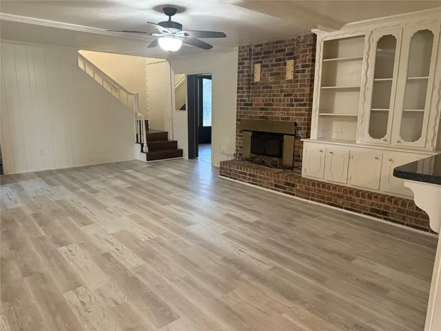 a view of an empty room with wooden floor fireplace and a window