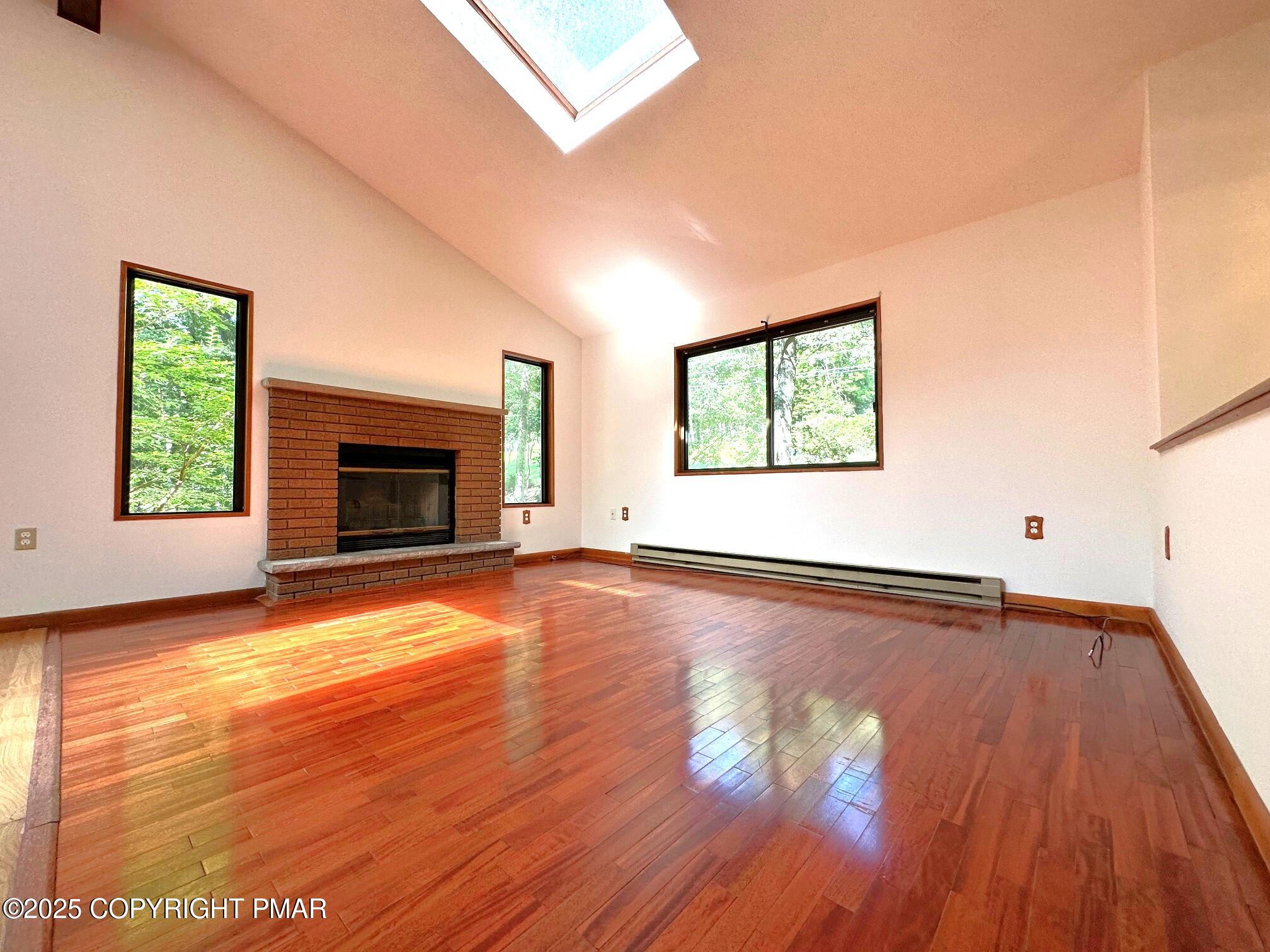 344 Pocono Boulevard, Unit 344 Bushkill, PA 18324 - Photo 2 of 20 an empty room with wooden floor fireplace and windows