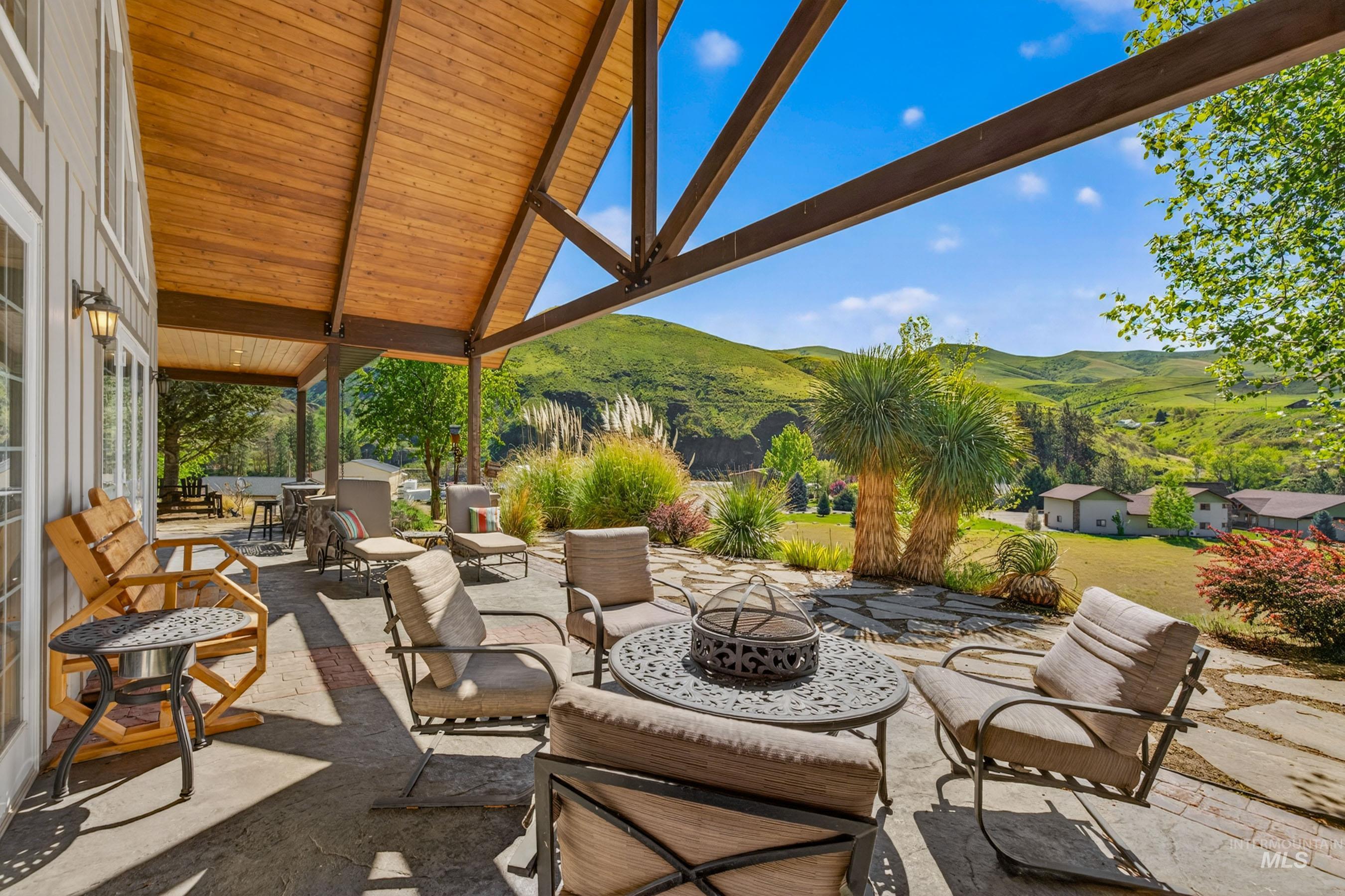 113 Deford Road White Bird, ID 83554 - Photo 30 of 49 Expansive covered patio featuring a wood-finish vaulted ceiling with exposed beams, flagstone patio, and mature landscaping
