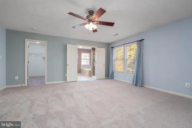 a view of an empty room with chandelier fan and windows