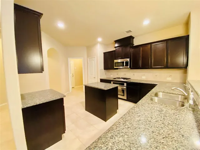 a large kitchen with granite countertop a stove a sink and a microwave