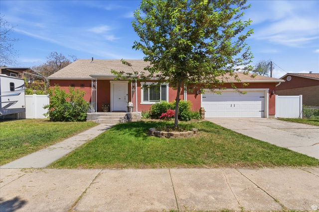 Red exterior with white trim, featuring a front porch with decorative columns, a two-car garage, and a concrete driveway