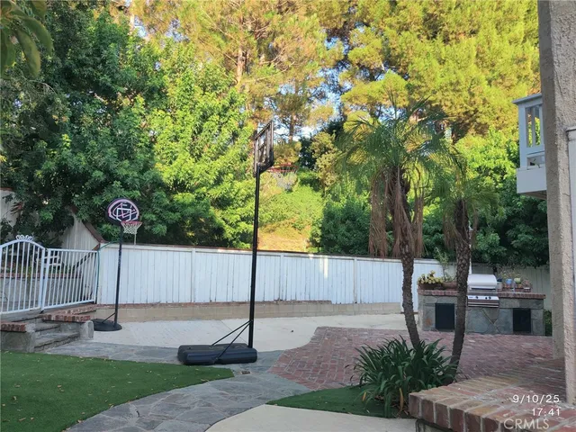 a view of a backyard with a tree and wooden fence