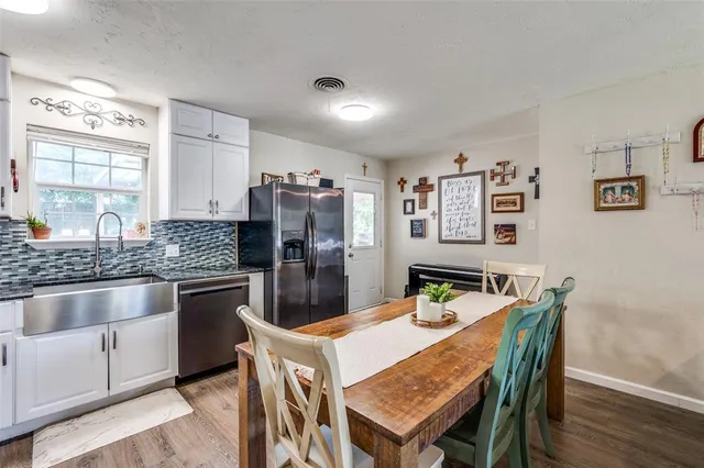 a kitchen with stainless steel appliances granite countertop a sink a stove a dining table and chairs