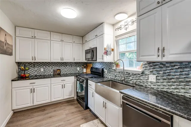a kitchen with granite countertop a sink a stove and cabinets