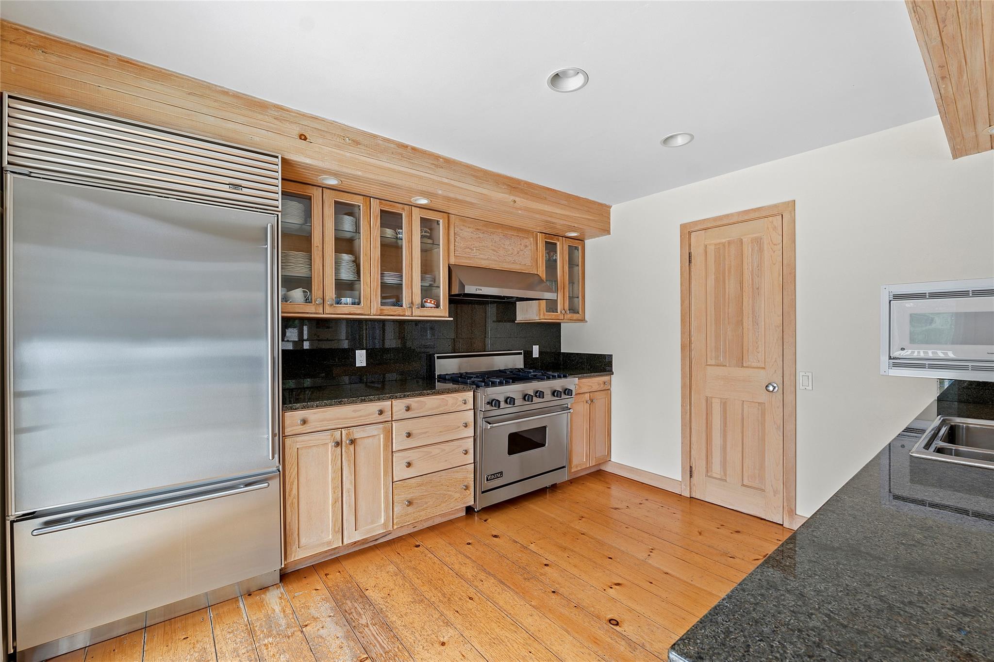 28 Georgica Close Road East Hampton, NY 11937 - Photo 5 of 23 Kitchen with light wood finished floors, built in appliances, wall chimney exhaust hood, glass insert cabinets, and decorative backsplash