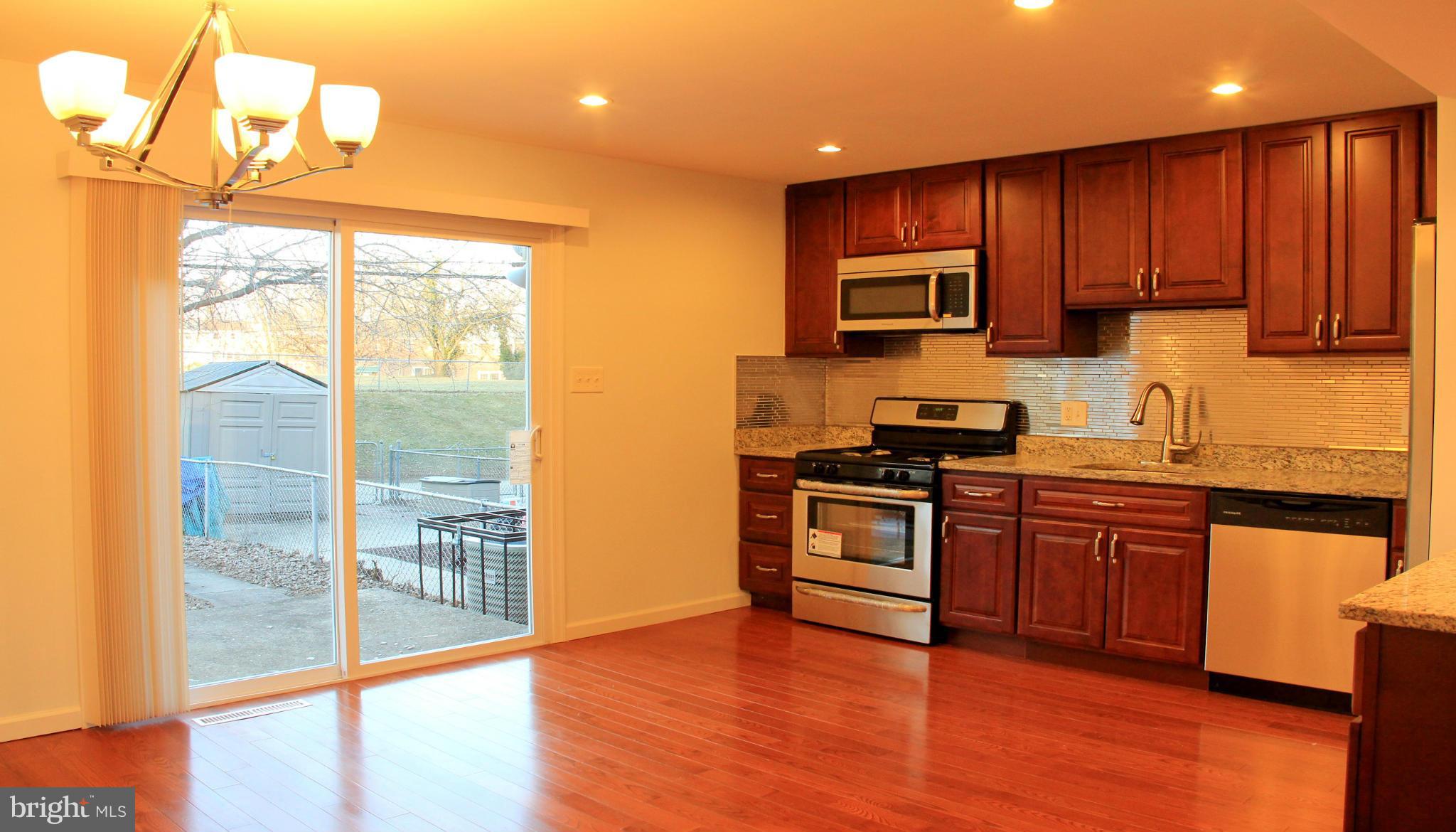 4772 Melbourne Road Baltimore, MD 21229 - Photo 18 of 30 a kitchen with stainless steel appliances granite countertop wooden cabinets a stove a sink and dishwasher with wooden floor