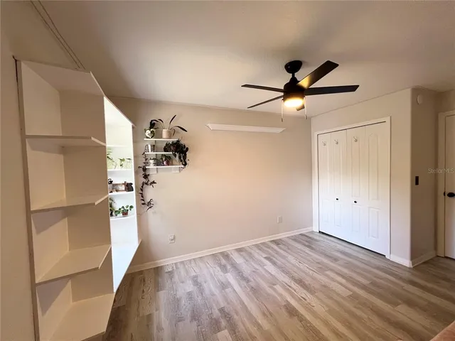 a view of empty room with wooden floor and fan
