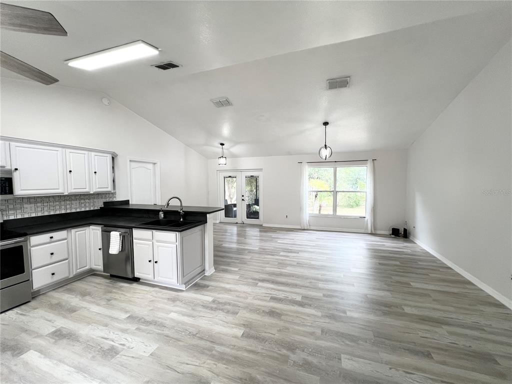 14906 Windy Mt Circle Clermont, FL 34711 - Photo 5 of 26 a large kitchen with stainless steel appliances granite countertop a stove a sink white cabinets and wooden floor