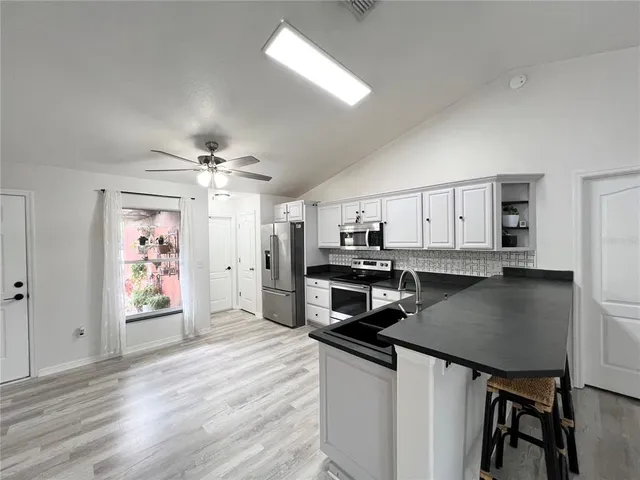 a kitchen with stainless steel appliances a kitchen island hardwood floor sink stove refrigerator and cabinets