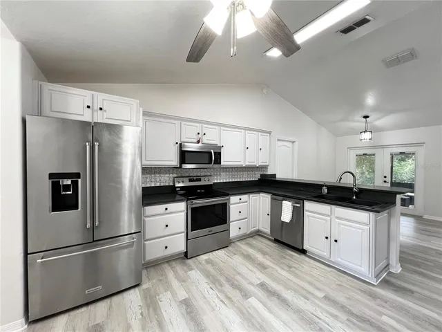a kitchen with stainless steel appliances a sink a stove a refrigerator and cabinets