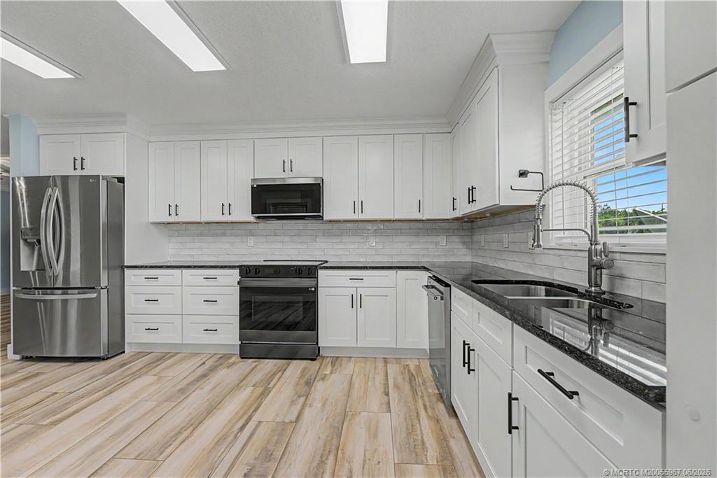 8200 Southwest Springhaven Avenue Indiantown, FL 34956 - Photo 6 of 35 a kitchen with granite countertop white cabinets and stainless steel appliances