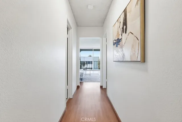 a view of a hallway with wooden floor and a bathroom