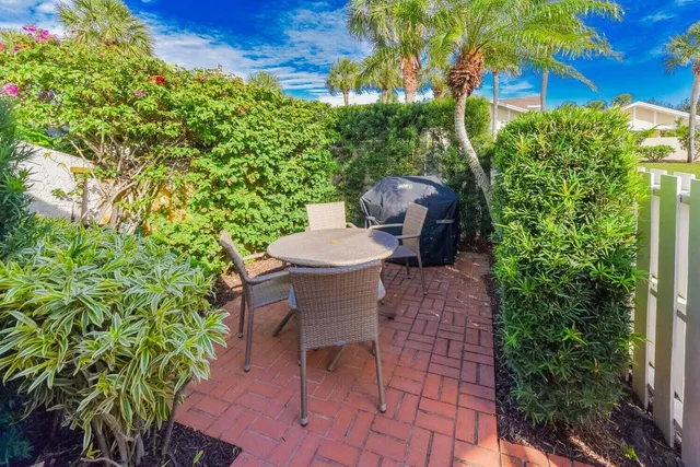 a view of a patio with table and chairs potted plants and large tree