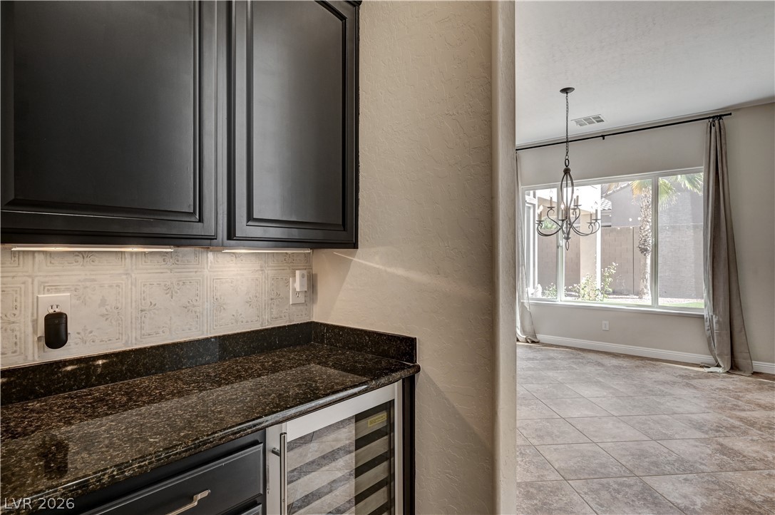 2793 Rosenhearty Drive Henderson, NV 89044 - Photo 11 of 85 This interior shot highlights a counter with dark cabinetry and a wine refrigerator, with a dining space visible beyond.