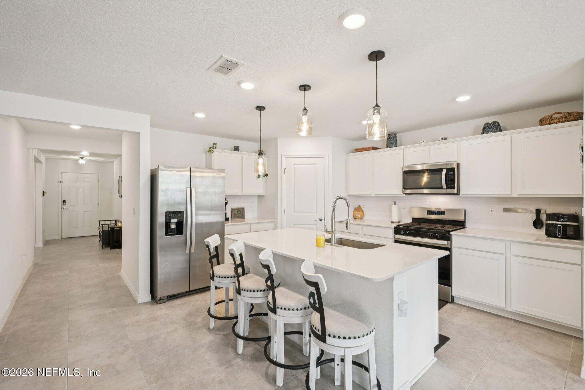 5508 Integrity Way Jacksonville, FL 32244 - Photo 18 of 34 a kitchen with stainless steel appliances kitchen island a table chairs refrigerator and microwave