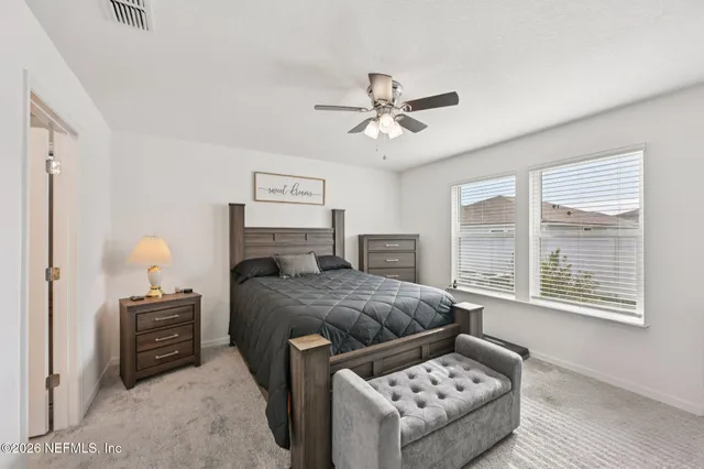 a bedroom with a bed a couches and large windows