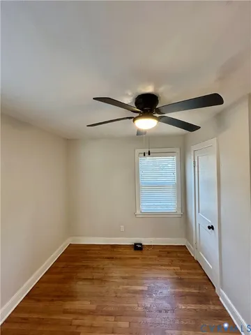 a view of an empty room with window and wooden floor