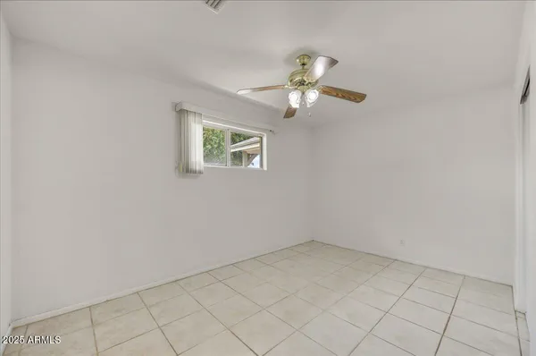 an empty room with windows and fan