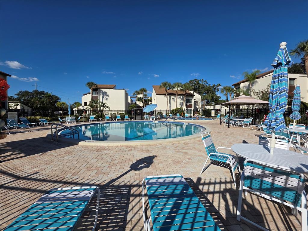 2207 Belleair Road, Unit B6 Clearwater, FL 33764 - Photo 17 of 21 a view of a patio with dining table and chairs with wooden floor and fence