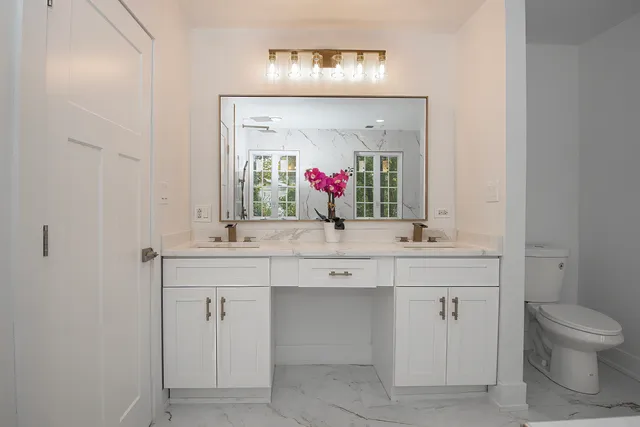 a bathroom with a double vanity sink mirror and toilet