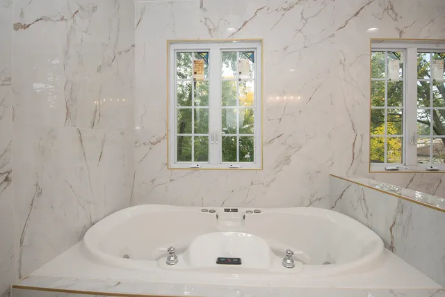 a white bath tub sitting in a bathroom next to a window