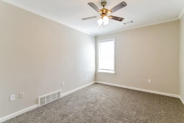 an empty room with windows and fan