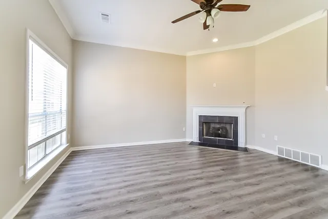 a view of an empty room with a window and wooden floor